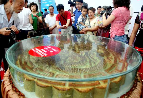 Visitors look at a huge moon cake exhibited in a food fair in Chengdu, Sichuan province, on Sunday. [Photo /China Daily]