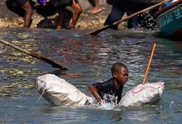 A kids tries to reach a boat to flee this destroyed city by boat in Port-au-Prince, Haiti, Jan. 20, 2010. (Xinhua/David de la Pas)