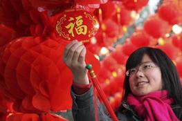A girl fondles an auspicious knot with Chinese Character of felicity inside the long corridor decorated with full range of florid red lanterns in the Ditan (Altar of the Earth) Park, as the festival atmosphere for the 25th Spring Festival Temple Fair slated from February 13 to 20, at Ditan Park is drumming up, in Beijing, February 4, 2010.