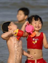 Two children amuse themselves in the sea in Haikou, capital of south China's Hainan Province, Feb. 10, 2010. According to local weather report, the highest temperature in the province has reached 35 degrees Celsius on Wednesday. A large number of people in Haikou went to the beach to cool themselves down. 