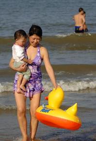 A woman carries a child walking on the beach in Haikou, capital of south China's Hainan Province, Feb. 10, 2010. According to local weather report, the highest temperature in the province has reached 35 degrees Celsius on Wednesday. A large number of people in Haikou went to the beach to cool themselves down. 