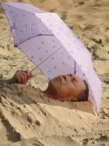 A tourist buries himself in the sands on the beach in Haikou, capital of south China's Hainan Province, Feb. 10, 2010. According to local weather report, the highest temperature in the province has reached 35 degrees Celsius on Wednesday. A large number of people in Haikou went to the beach to cool themselves down. 