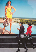 Two women walk past a Louis Vitton advertisement on a road in Wuxi, East China's Jiangsu province. [Qiu Daochen/For China Daily]