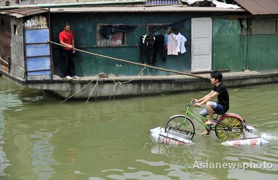 A man rides across the Hanjiang River (a tributary of the Yangtze) in Wuhan, capital of Central China&apos;s Hubei province on June 16, 2010. The bike, with eight big empty water bottles at the bottom, was fashioned by Li Weiguo, a retiree. Li hopes his invention can be put into production someday so that people can ride it for fun.[Asianewsphoto]