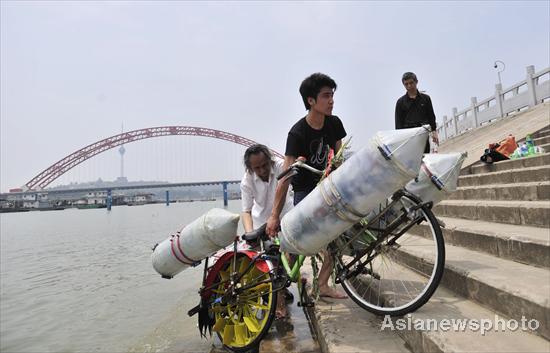 A man pulls his bike after crossing the Hanjiang River (a tributary of the Yangtze) in Wuhan, capital of Central China&apos;s Hubei province on June 16, 2010. [Asianewsphoto] 