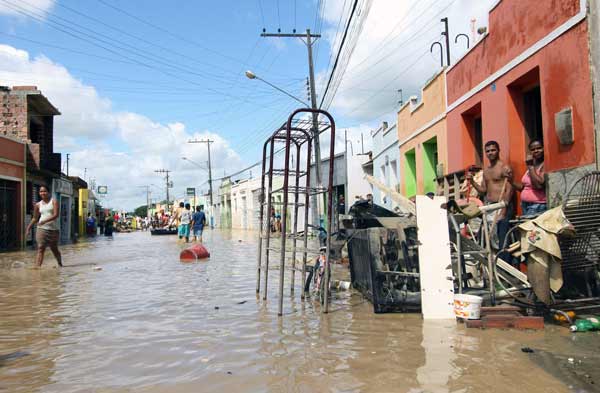 Residents walk in a flooded street in Jacuipe, in northeastern Alagoas state, Brazil, Monday, June 21, 2010. [Xinhua]