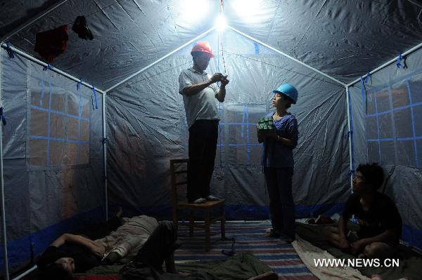 Electricians fix live wires in a makeshift tent serving for the people affected by floods in Wuzhou City of east China's Jiangxi Province, June 23, 2010. A total of 17 evacuation centers in Wuzhou had received 20,014 people affected by floods until 19:00 Wednesday. [Xinhua] 