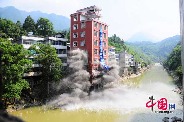 A seven-story illegal building is demolished by a blast along a river in Hefeng County, Central China&apos;s Hubei province on July 29, 2010. The illegal building is surrounded by homes, so local authorities dispatched technical professionals to check on the resident&apos;s houses and made a plan to clean up the debris in the river after the blast. [CFP] 