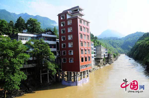 A seven-story illegal building is demolished by a blast along a river in Hefeng County, Central China&apos;s Hubei province on July 29, 2010. The illegal building is surrounded by homes, so local authorities dispatched technical professionals to check on the resident&apos;s houses and made a plan to clean up the debris in the river after the blast. [CFP] 