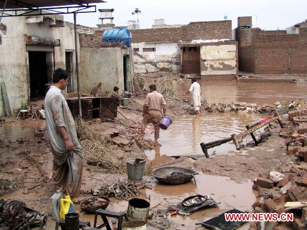 People clear debris as their houses were flooded following heavy monsoon rains in northwest Pakistan&apos;s Nasir-Bagh on Aug. 1, 2010. The current horrible wave of floods and landslides triggered by torrential monsoon rains has killed more than 900 people in Pakistan while 1 million people have become homeless as the flood is now hitting western and southern parts of the country. [Saeed Ahmad/Xinhua]