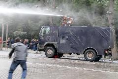 A protester throws stones at a water cannon in Tirana, Albania, Jan. 21, 2011. Two people were killed from firearms after a protest rally by Albania's opposition Socialist Party turned into a riot in front of the government building for three hours before the protesters disbanded. [Yang Ke/Xinhua]