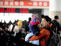 A woman holding her child waits for getting on a train at the Shenyang North Railway Station, in Shenyang, capital of northeast China&apos;s Liaoning Province, Jan. 25, 2011. According to an estimate based on the sales of train tickets, the station will witness a travel peak from Jan. 31 to Feb. 1, as the eve of the Chinese Spring Festival falls on Feb. 3 this year, which by tradition Chinese people should spend at home with family memebers. [Xinhua] 