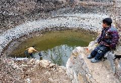 A villager collects water from a pond to be dried up in Jiangling Village, Song County of central China&apos;s Henan Province, Feb. 22, 2011. Suffering from the most serious drought within 50 years, Henan Province has no effective rainfall for more than 130 days, with 29 million mu (1.94 million hectare) paddy fields and drinking water in some mountainous regions affected. [Xinhua] 