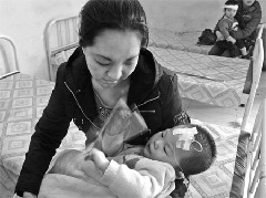 A woman takes care of her baby, who fell sick after drinking tap water contaminated by e-coli bacteria, at the people's hospital in Yilan county, Heilongjiang province, on Sunday. [China Daily] 