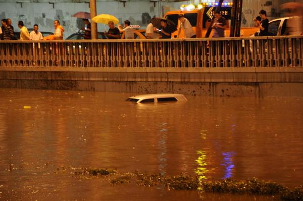 A car is submerged by rain waters in downtown Beijing, July 26, 2011. [Photo/Xinhua] 