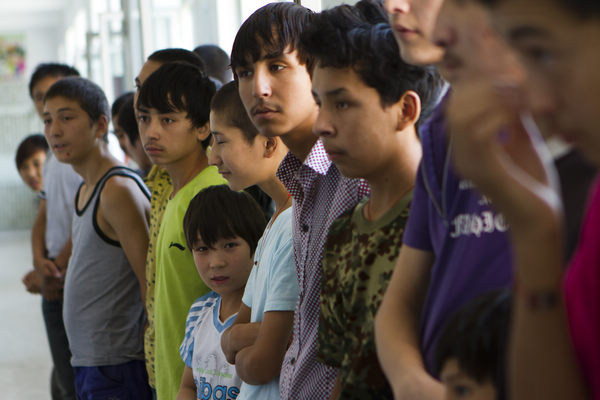 Vagrant children from the Xinjiang Uygur autonomous region rescued from criminal gangs and sent back to the region by the authorities in places where they had been coerced into stealing, stand in line waiting for assistance and aid at a vagrant children relief center in Urumqi, the regional capital, on Aug 4.
