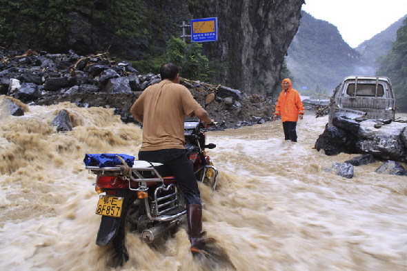 Vehicles trudge on a flooded road in Xingshan County of Yichang City, central China's Hubei Province, Aug. 22, 2011. [Xinhua] 