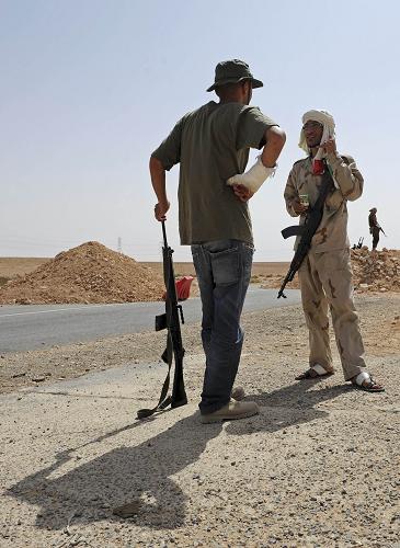 NTC fighters chat after securing a new checkpoint on the road between Tarhuna to Bani Walid, southeast of Tripoli, on September 4, 2011, as fighters loyal to Libya's new rulers advanced on one of Moamer Kadhafi's last remaining bastions. 