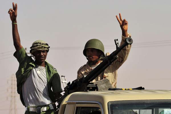 Anti-Gadhafi fighters gesture as they move to the front line, 90 km east of Sirte, from Om El Qandil, 90 km west of Ras Lanuf September 6, 2011.[Agencies]