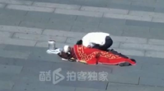 A frame grab from the video clip uploaded to Ku6.com shows the beggar and an old woman lying on the ground beside him in Xidan, downtown Beijing. [Photo/Ku6.com] 