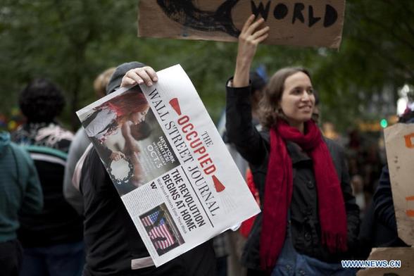 A protester demonstrates a copy of 'the Occupied Wall Street Journal' near Wall Street in New York, the United States, Oct. 2, 2011. Protest against Wall Street corporate greed continues in New York after the arrest on Sunday of over 700 protesters who blocked traffic on the Brooklyn Bridge.[Fan Xia/Xinhua] 