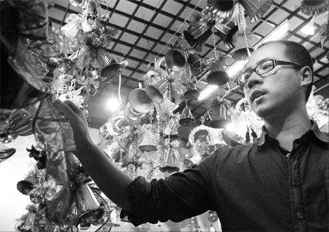 A businessman examining Christmas decorations at his store in Yiwu of East China's Zhejiang province. The man, identified only as Mr Tang, said overseas orders for Christmas products he received this year increased at least 50 percent from last year. [Yong Kai/China Daily]