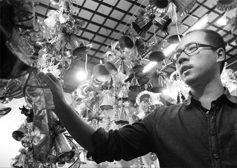 A businessman examining Christmas decorations at his store in Yiwu of East China's Zhejiang province. The man, identified only as Mr Tang, said overseas orders for Christmas products he received this year increased at least 50 percent from last year. [Yong Kai/China Daily]
