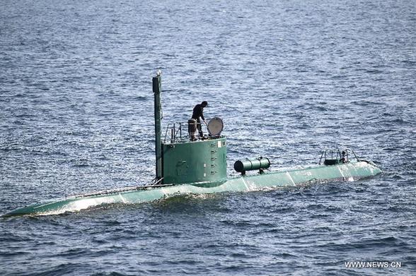 A soldier stands at a submarine during Iranian naval maneuvers dubbed Velayat 90 on the Sea of Oman, Iran, Dec. 27, 2011. [Ali Mohammadi/Xinhua]