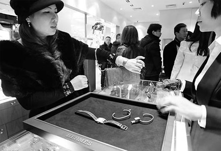 A woman trying on new designs of Herms wristwatches at the French brand's franchise store in Wenzhou, Zhejiang province. Herms at present has 20 shops in China, fewer than half of the number of shops it has in Japan. [China Daily]