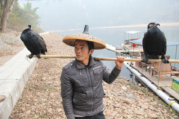 Yang Guihua, used to be a fisherman, now makes money by charging tourists to be photographed with his two cormorants. [China Daily] 