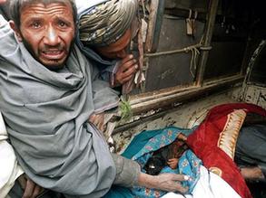 A mourner cries over the bodies of Afghan civilians, allegedly shot by a rogue US soldier, seen loaded into the back of a truck in Alkozai village of Panjwayi district, Kandahar province on March 11, 2012. [Xinhua]