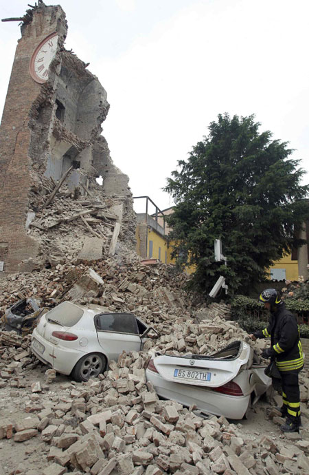 A firefighter stands next to damaged cars in the rubble near the old tower of Delle Rocche castle after an earthquake in Finale Emilia May 20, 2012.[Photo/Agencies] 