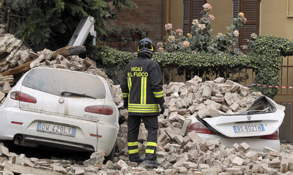 A firefighter stands next to damaged cars after an earthquake in Finale Emilia May 20, 2012. A strong earthquake rocked a large swathe of northern Italy early on Sunday, killing at least three people and causing serious damage to the area's cultural heritage.[Photo/Agencies]