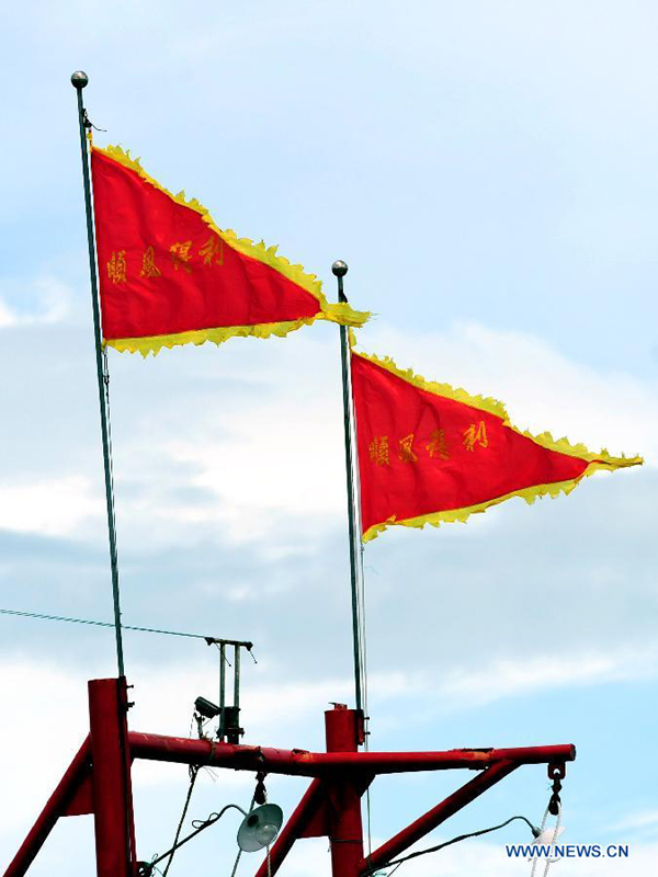 Photo taken on Aug. 1, 2012 shows the flags hanging on the fishing boat in Sanya, south China&apos;s Hainan Province. As the two-and-half-month summer fishing moratorium in the South China Sea ended Wednesday, fishing boats will be back to work.