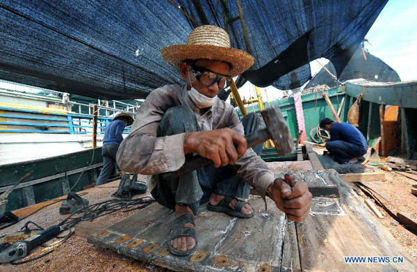 A fisherman fixes the deck of a fishing boat in Tanmen Town of Qionghai, south China&apos;s Hainan Province, Aug. 1, 2012. As the two-and-half-month summer fishing moratorium in the South China Sea ended Wednesday, fishing boats will be back to work.