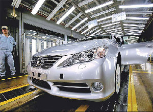 A worker stands next to a Toyota Motor Corp vehicle at the company's assembly line in Tianjin. According to a report on Sunday by the Japanese newspaper Asahi Shimbun, the future of Toyota's fourth factory in Tianjin will hinge on the recovery of sales in China. [China Daily]