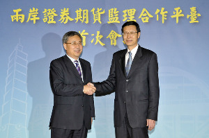 Guo Shuqing (left), chairman of the China Securities Regulatory Commission, shakes hands with Chen Yuh-chang, chairman of the Financial Supervisory Commission, in Taipei on Tuesday. The mainland will open its securities and futures markets to Taiwan investors through the Renminbi Qualifi ed Foreign Institutional Investor program. [Chen Zhentang /China Daily]
