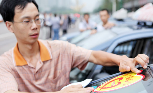 A cab driver pastes a &apos;free for gaokao students&apos; sticker on his windshield in Chongqing on Thursday. [China Daily]