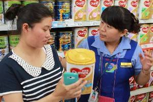Mu Liping (left) checks with a saleswoman at a supermarket in Beijing on Sunday whether her newly bought Dumex baby formula should be recalled. Dumex announced it was recalling 12 batches of products in China that may be contaminated. Mu found her purchase didn't belong to the recalled batches and left with the baby power.