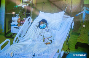 Photo taken on April 13, 2013 shows a screen showing a seven-year-old girl, who was infected with the H7N9 strain of bird flu, receiving medical treatment in the Beijing Ditan Hospital, during a press conference held by the hospital in Beijing, capital of China. [Photo/Xinhua] 